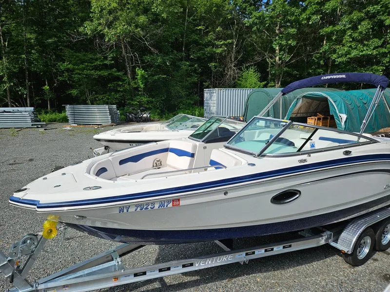 Slide: The Image of 2019 Chaparral 246 SSi boat on trailer, parked outdoors with trees in background. - 2