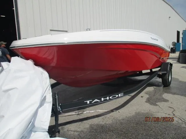 Slide: The Image of 2024 Tahoe T18 boat with red hull on trailer, parked outside a building. - 2