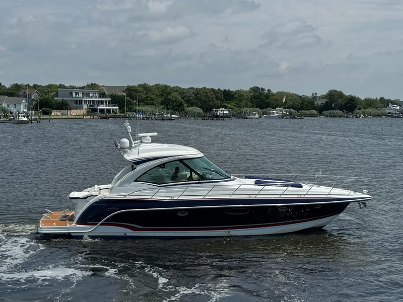 Slide: The Image of 2013 Formula 45 Yacht cruising on a calm river with houses in the background. - 2