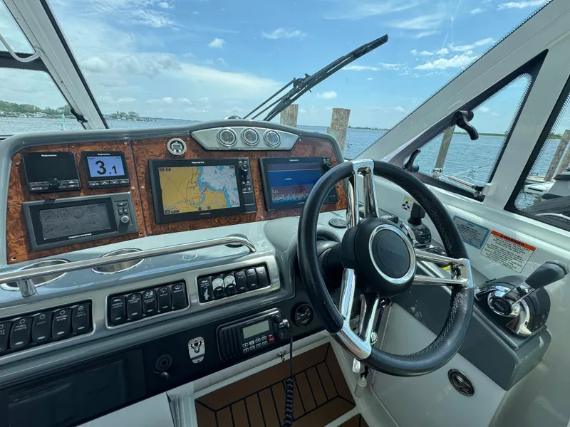 Slide: The Image of 2013 Formula 45 Yacht helm with navigation screens and steering wheel, docked by the water. - 28