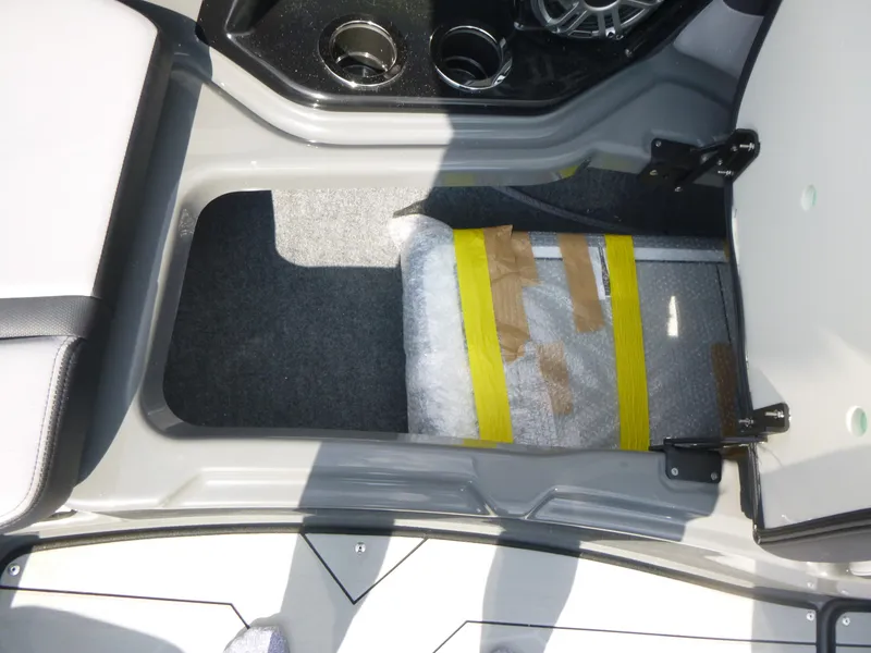 Slide: The Image of 2025 Yamaha Boats 255XE interior storage compartment with cup holders and wrapped package. - 12