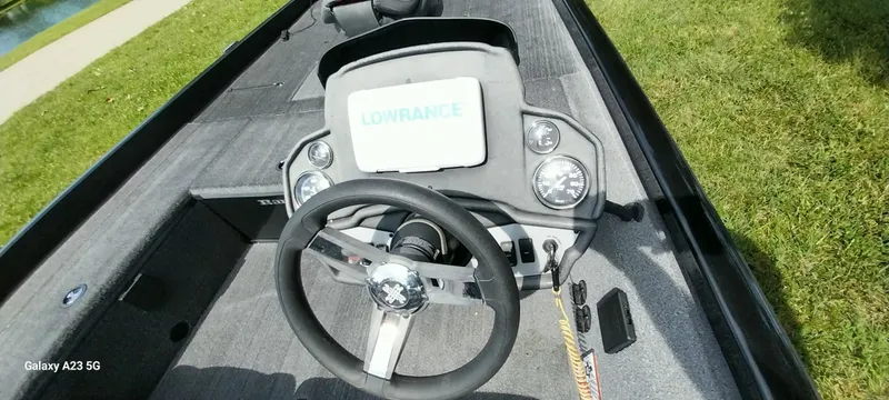 Slide: The Image of 2024 Ranger RT178C boat dashboard with steering wheel and Lowrance display, parked on grass. - 10