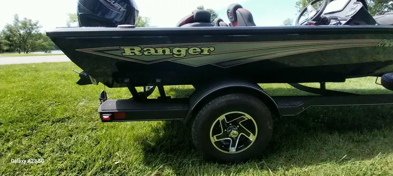 Slide: The Image of 2024 Ranger RT178C boat on grass, showcasing sleek design and trailer wheel. - 4