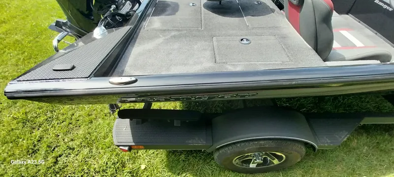 Slide: The Image of 2024 Ranger RT178C boat on trailer, featuring spacious deck and seating, parked on grass. - 5