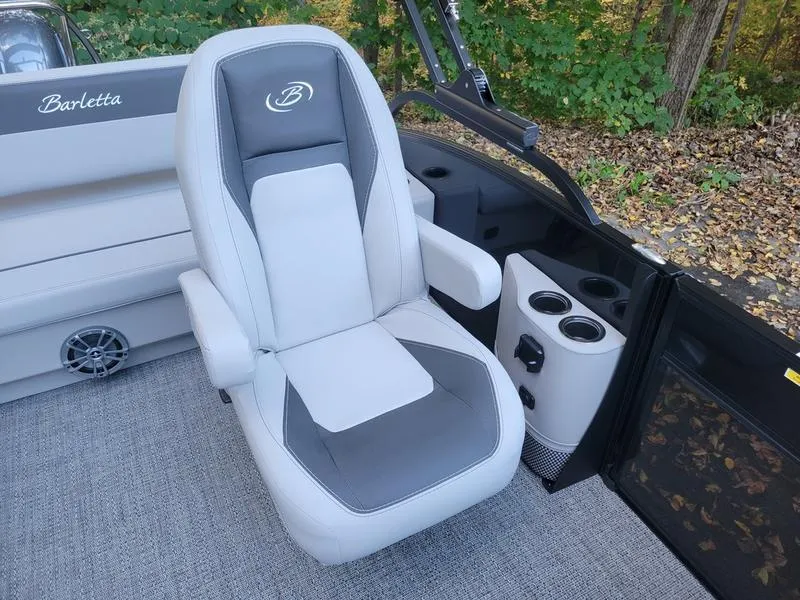 Slide: The Image of 2025 Barletta A20UC boat seat with cup holders, surrounded by lush greenery. - 13