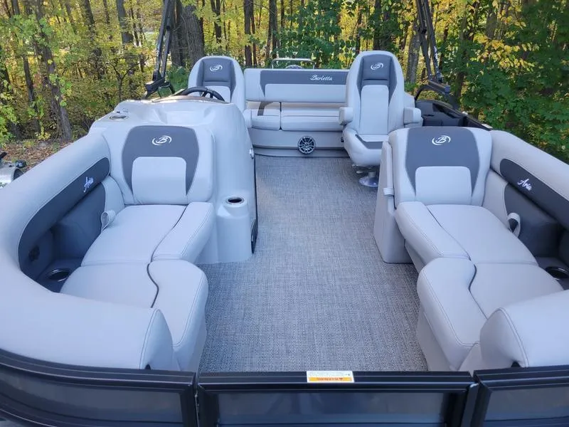 Slide: The Image of 2025 Barletta A20UC pontoon boat interior with gray seating and forest backdrop. - 7