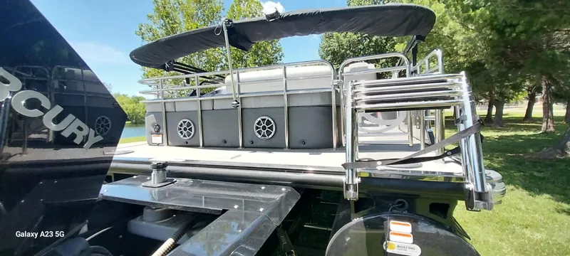 Slide: The Image of 2023 Regency 250 LE3 Sport boat with Mercury engine, docked near lush greenery. - 14