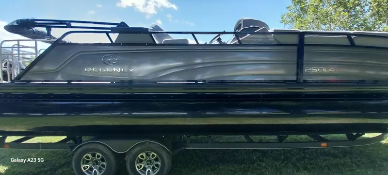 Slide: The Image of 2023 Regency 250 LE3 Sport pontoon boat on trailer, side view, outdoors. - 19