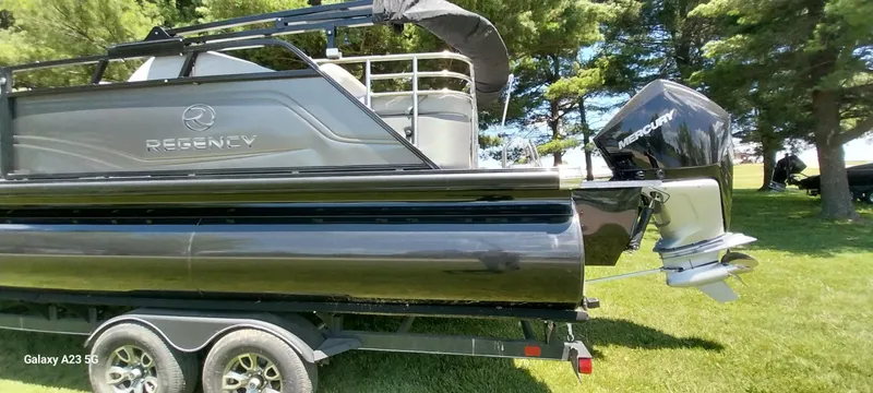 Slide: The Image of 2023 Regency 250 LE3 Sport pontoon boat with Mercury engine on a trailer. - 2