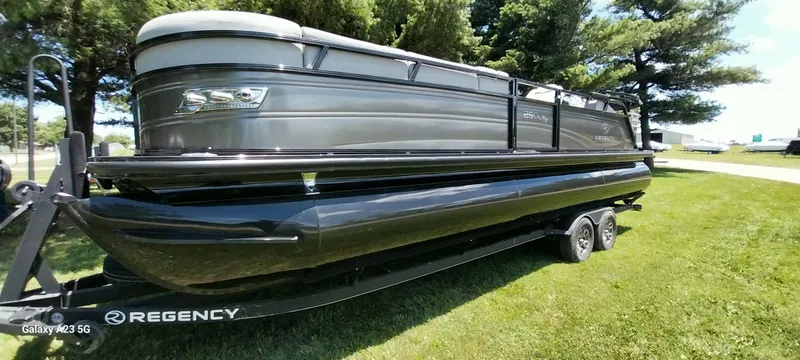 Slide: The Image of 2023 Regency 250 LE3 Sport pontoon boat on trailer, parked on grass. - 27
