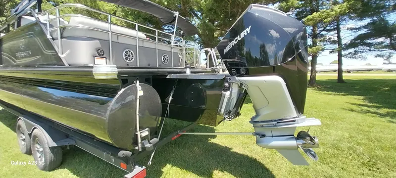 Slide: The Image of 2023 Regency 250 LE3 Sport pontoon boat with Mercury outboard engine on a grassy area. - 28