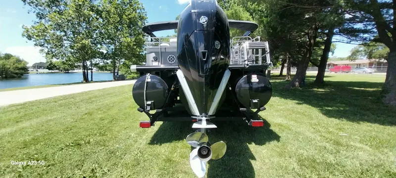 Slide: The Image of 2023 Regency 250 LE3 Sport boat on grass, near a lake, surrounded by trees. - 31