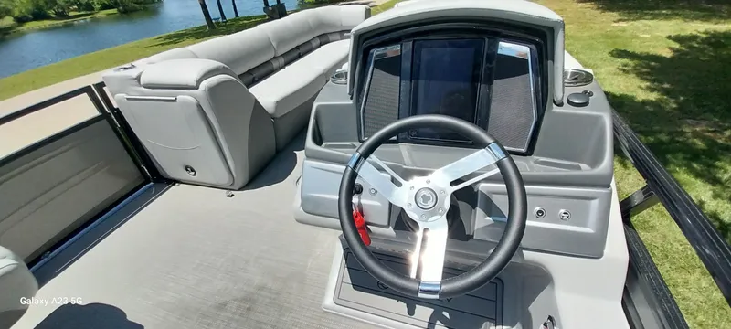 Slide: The Image of 2023 Regency 250 LE3 Sport boat interior with steering wheel and seating, near a lake. - 38