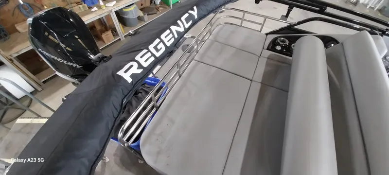 Slide: The Image of 2023 Regency 250 LE3 Sport boat interior with seating and Mercury engine in a workshop. - 8