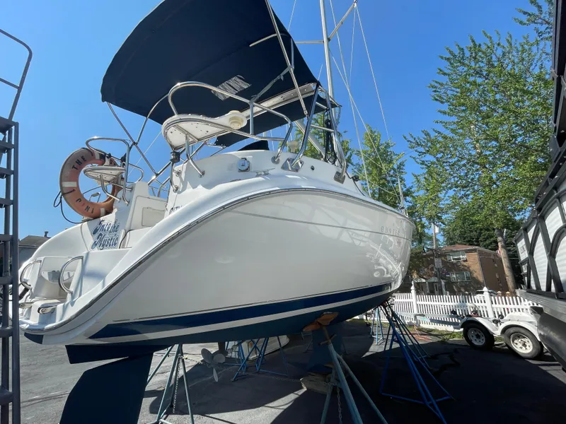 The Image of 2001 Hunter 306 sailboat on stands, blue sky background, trees nearby. - 0