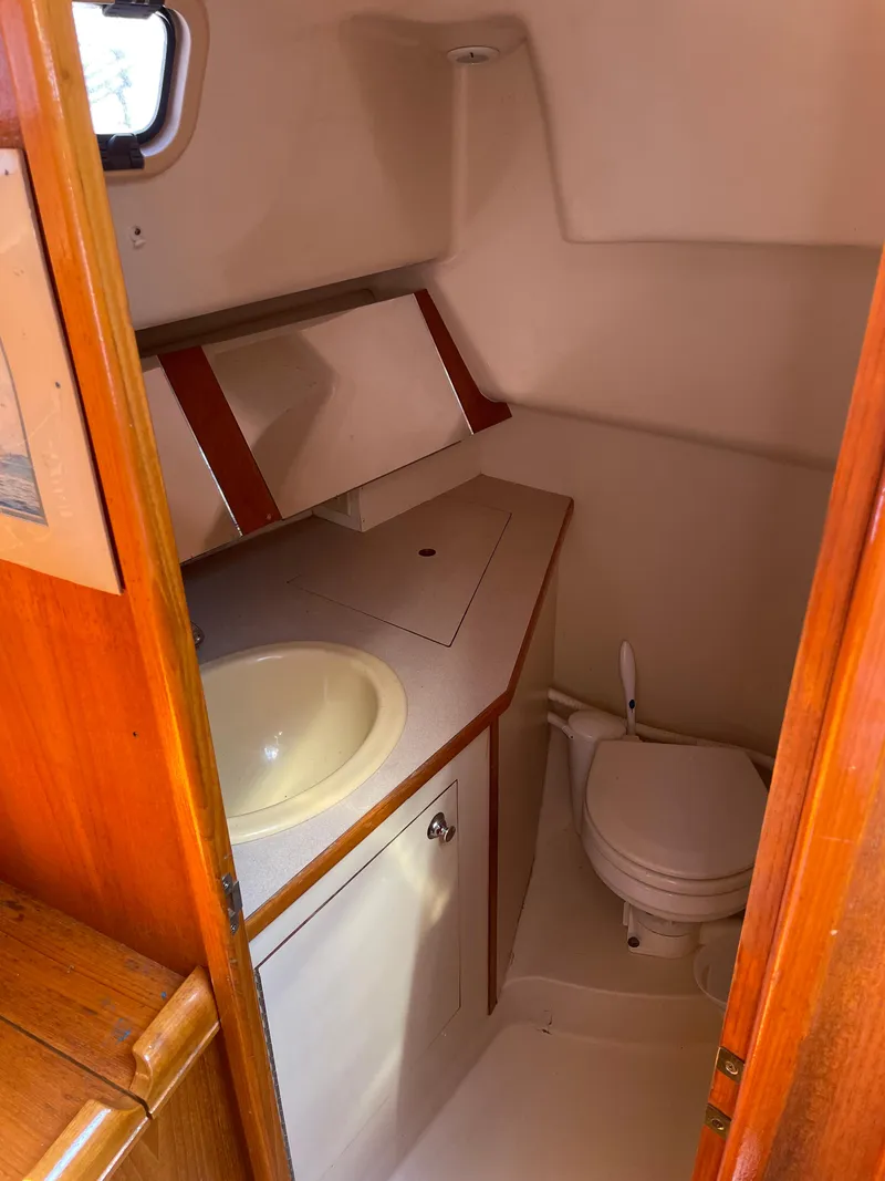 Slide: The Image of Compact bathroom in a 2001 Hunter 306 sailboat, featuring a sink and toilet. - 12