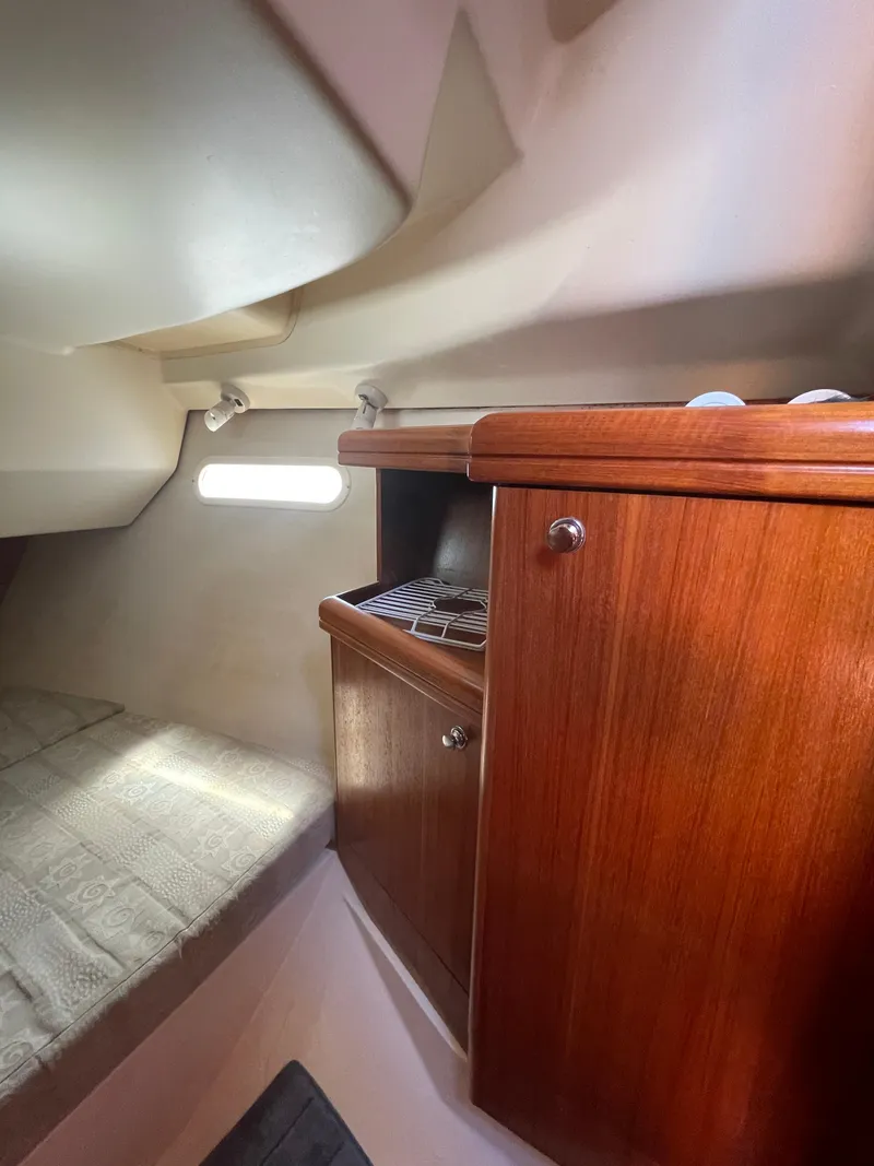 Slide: The Image of Interior of a 2001 Hunter 306 sailboat with wooden cabinetry and cozy sleeping area. - 13