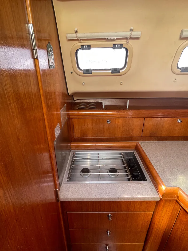Slide: The Image of 2001 Hunter 306 yacht interior kitchen with stove, wooden cabinetry, and porthole windows. - 16