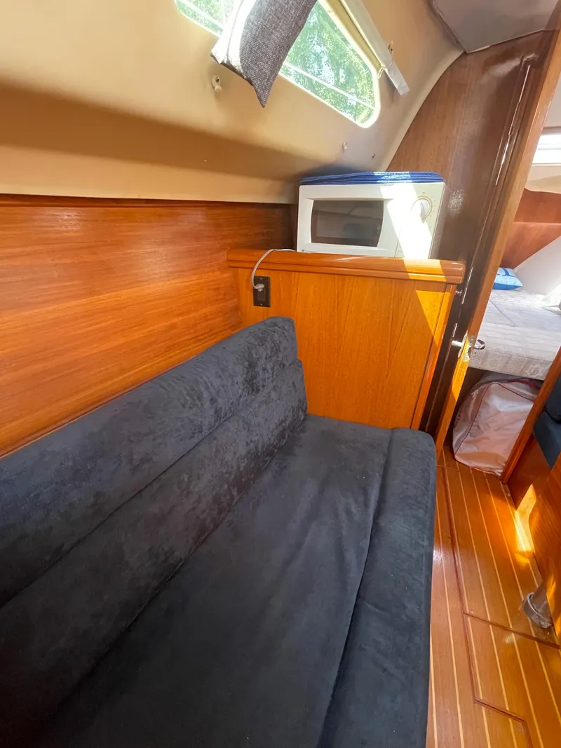 Slide: The Image of Interior of a 2001 Hunter 306 sailboat with a black sofa and microwave. - 21