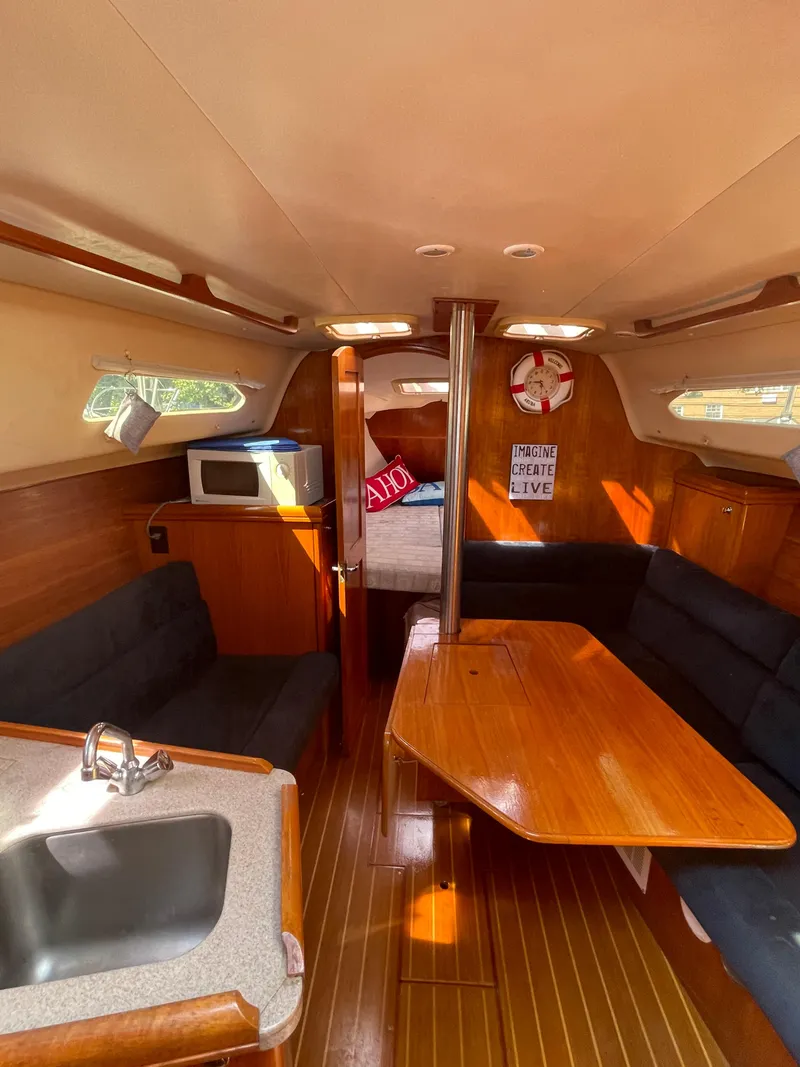 Slide: The Image of Interior of 2001 Hunter 306 sailboat with wood finish and cozy seating area. - 25