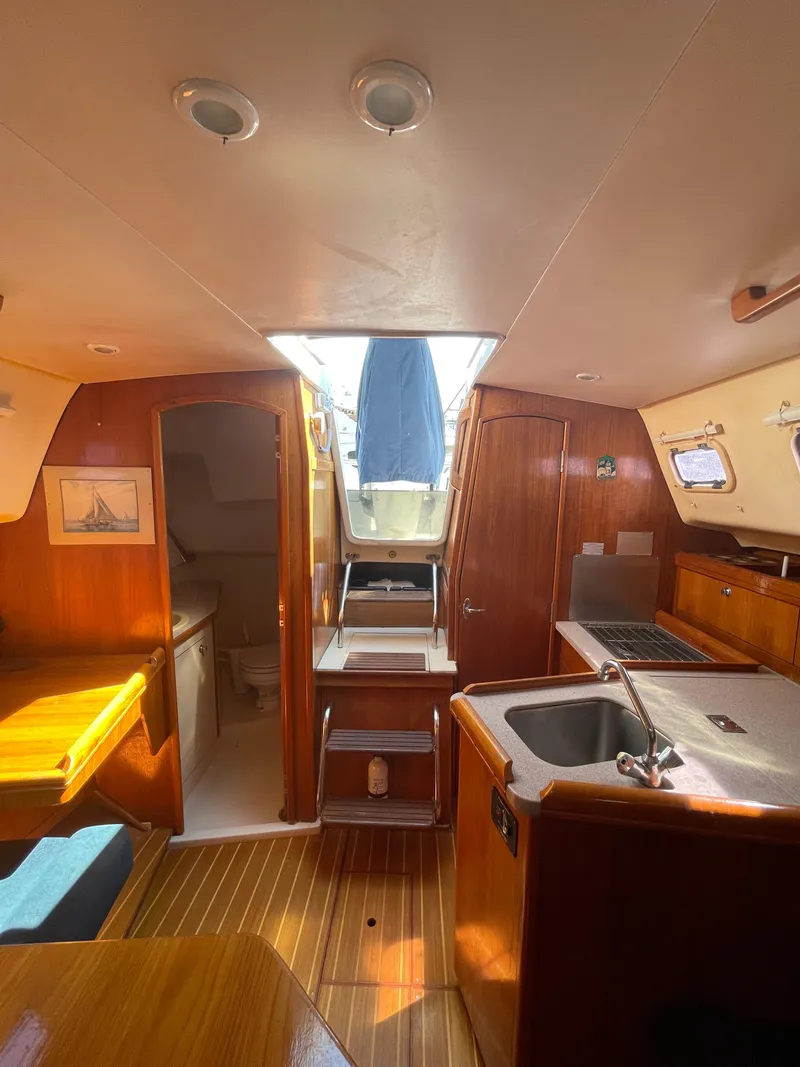 Slide: The Image of Interior of 2001 Hunter 306 sailboat with wood finish and compact kitchen area. - 7