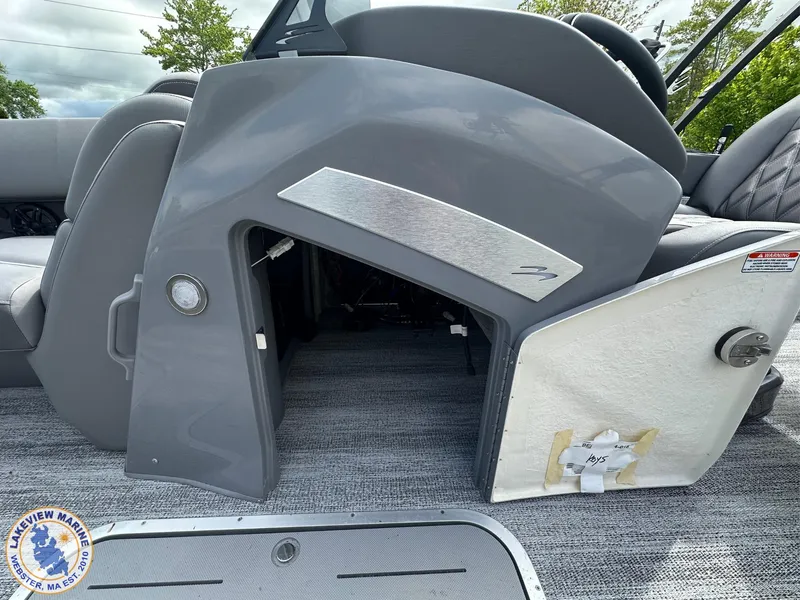 Slide: The Image of 2025 Bennington 23 LXSSB boat interior with open storage compartment and gray seating. - 6