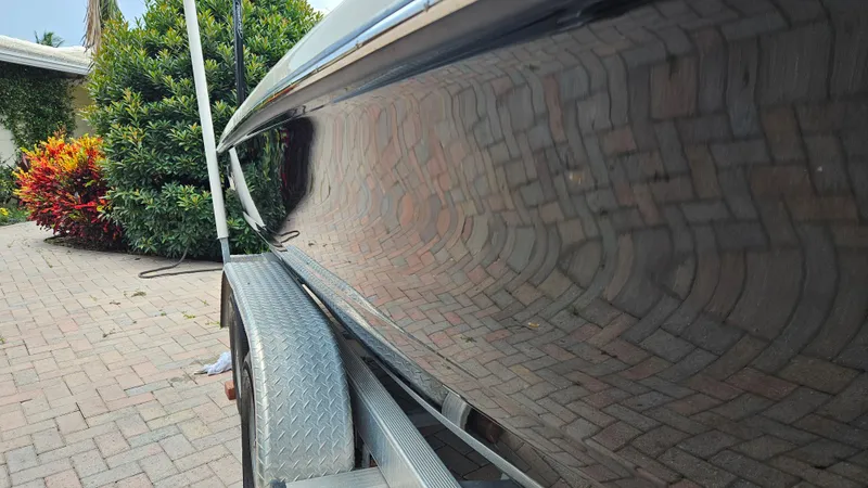 Slide: The Image of 2021 Scout 231 XS boat on trailer, reflecting brick pavement and lush greenery. - 12