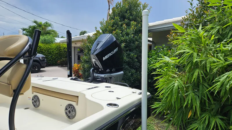 Slide: The Image of 2021 Scout 231 XS boat with Mercury engine, parked near lush greenery. - 16