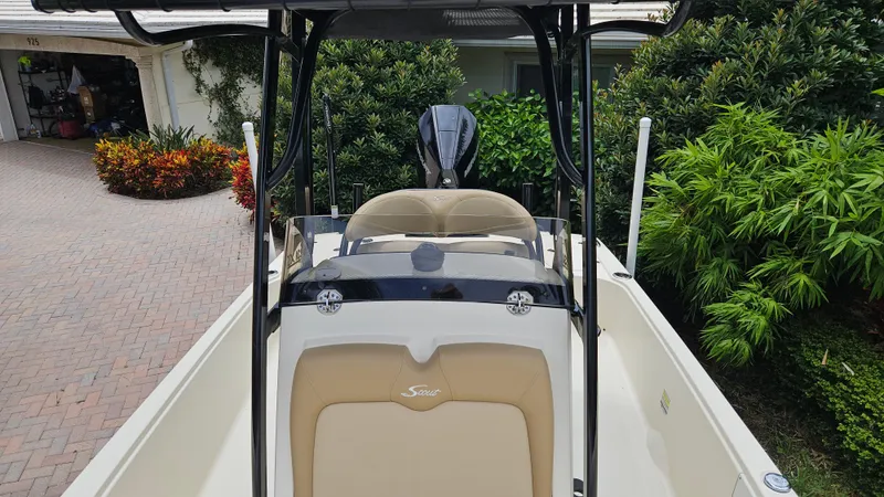 Slide: The Image of 2021 Scout 231 XS boat with beige seating, parked near lush greenery. - 36