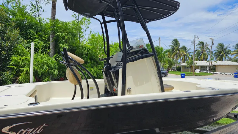 Slide: The Image of 2021 Scout 231 XS boat with T-top, parked outdoors, surrounded by palm trees. - 4
