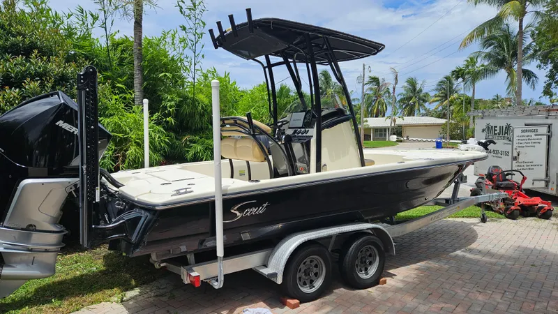 Slide: The Image of 2021 Scout 231 XS boat on trailer, parked outdoors with lush greenery and palm trees. - 6