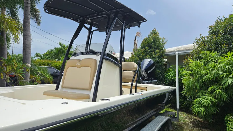 Slide: The Image of 2021 Scout 231 XS boat with T-top, parked near tropical foliage. - 7