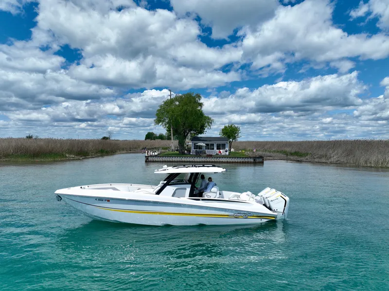 Slide: The Image of 2024 Sunsation 34 CCX boat cruising on clear water under a partly cloudy sky. - 0