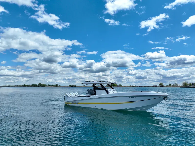 Slide: The Image of 2024 Sunsation 34 CCX boat cruising on a sunny day with blue skies and clouds. - 1