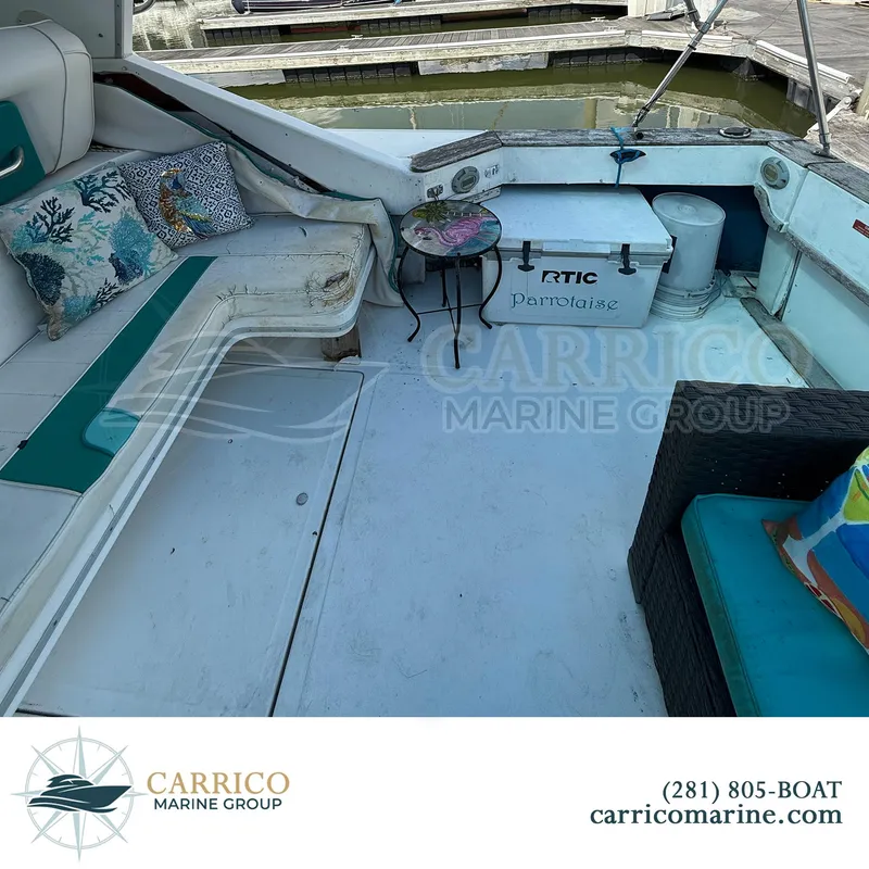 Slide: The Image of 1990 Sea Ray 390 Express Cruiser interior with seating, cushions, and a small table. - 10