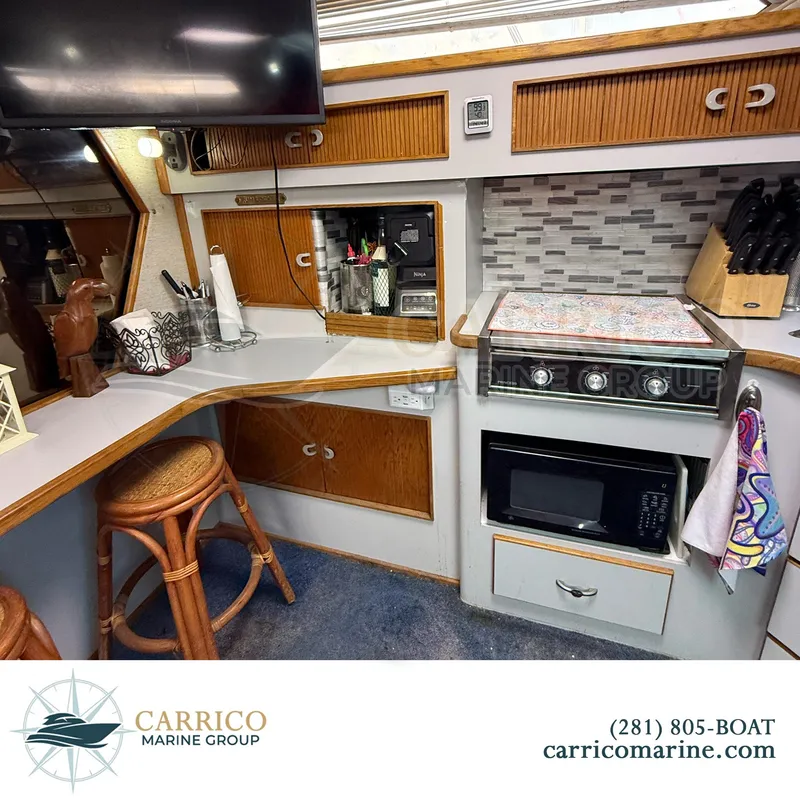 Slide: The Image of 1990 Sea Ray 390 Express Cruiser interior kitchen with stove, microwave, and wooden cabinetry. - 21