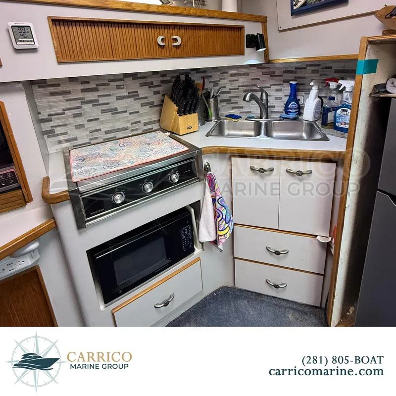 Slide: The Image of 1990 Sea Ray 390 Express Cruiser kitchen with stove, microwave, sink, and storage cabinets. - 22