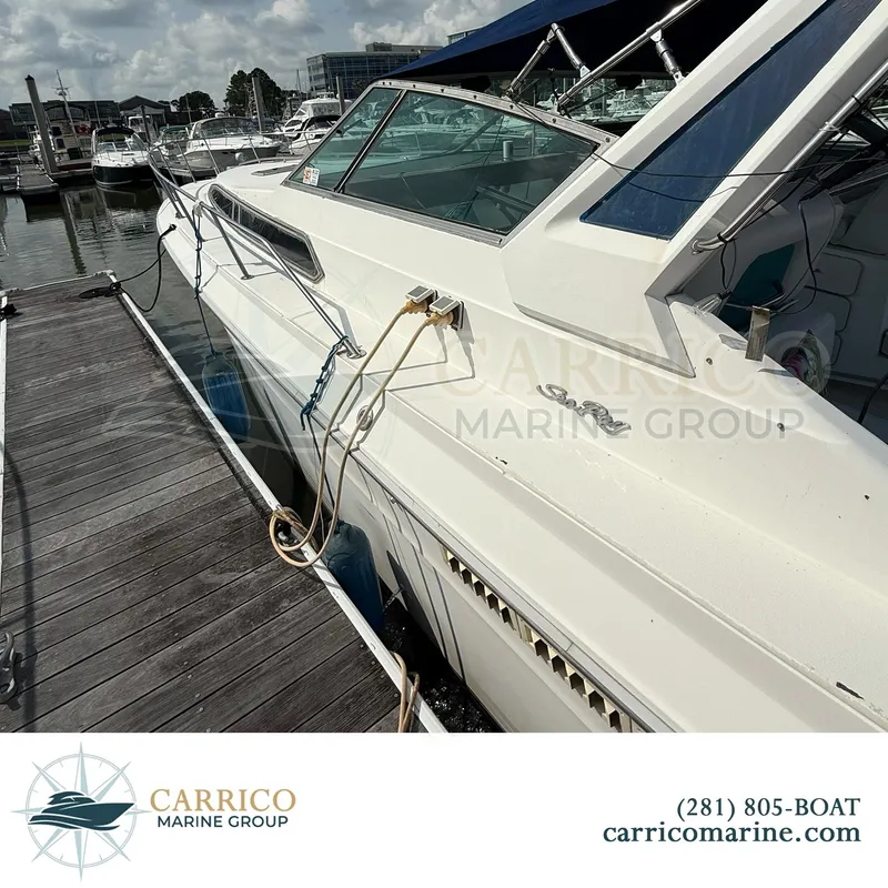Slide: The Image of 1990 Sea Ray 390 Express Cruiser docked at marina, side view with blue canopy. - 3