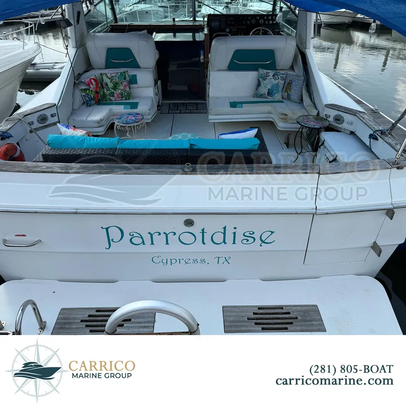 Slide: The Image of 1990 Sea Ray 390 Express Cruiser named "Parrotdise" docked, featuring comfortable seating and decor. - 6