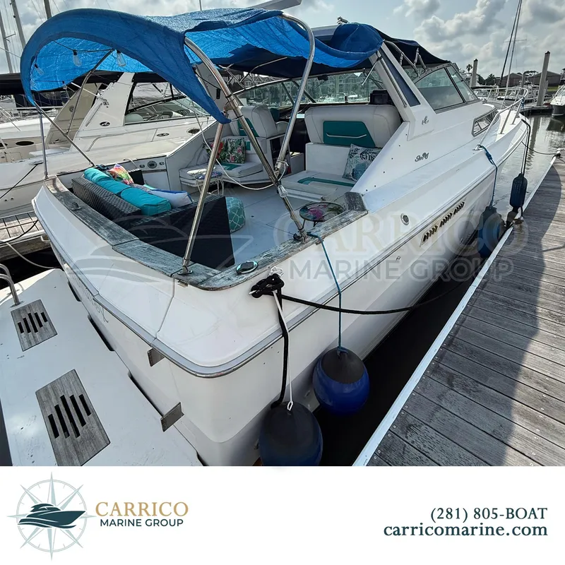 Slide: The Image of 1990 Sea Ray 390 Express Cruiser docked, featuring a blue canopy and spacious deck. - 7