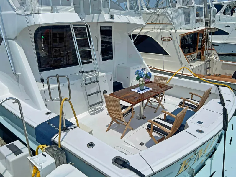 Slide: The Image of Hatteras 60 Convertible 2000 yacht with outdoor seating and table, docked at marina. - 3