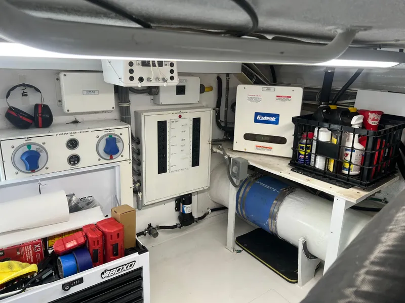 Slide: The Image of Engine room of a 2000 Hatteras 60 Convertible yacht with control panels and maintenance supplies. - 43