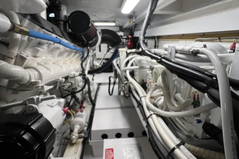 Slide: The Image of Engine room of a 2000 Hatteras 60 Convertible yacht, showcasing complex machinery and wiring. - 49