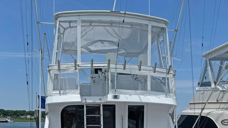 Slide: The Image of 2000 Hatteras 60 Convertible yacht with enclosed flybridge, docked under clear blue sky. - 5