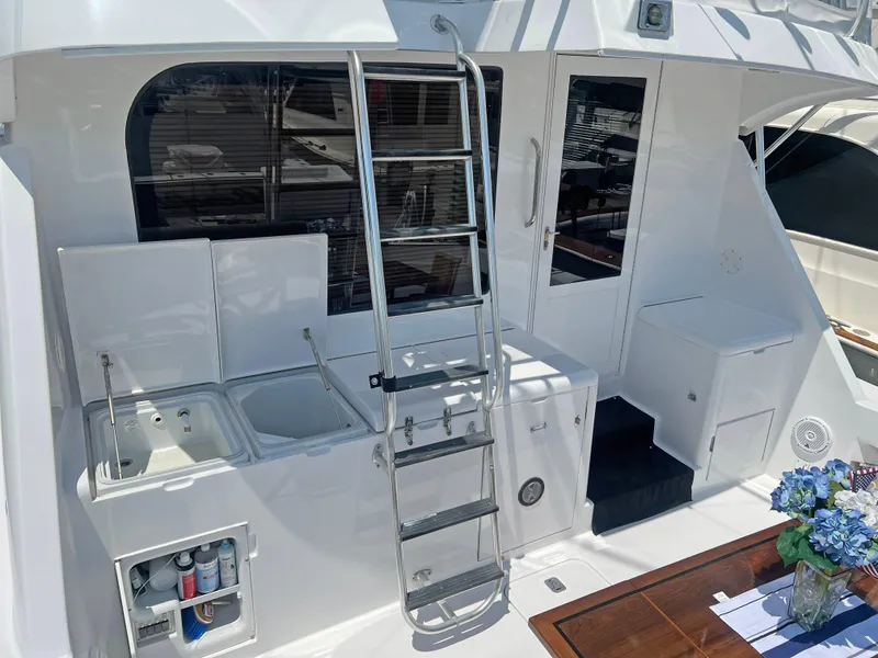 Slide: The Image of Hatteras 60 Convertible 2000 yacht deck with ladder, seating, and floral arrangement. - 7