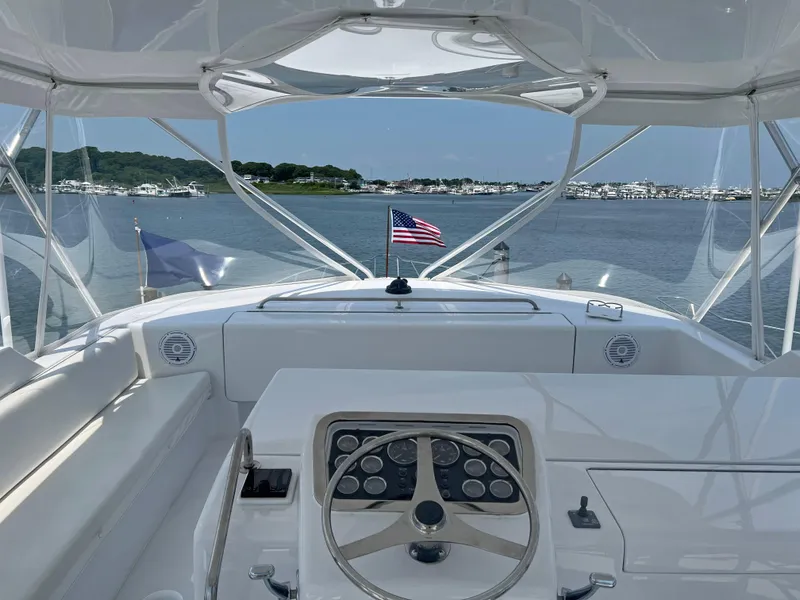 Slide: The Image of Helm view of 2000 Hatteras 60 Convertible yacht with American flag, docked in marina. - 8