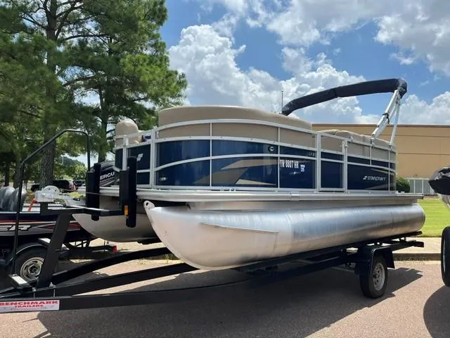 Slide: The Image of 2023 Starcraft LX18 R pontoon boat on trailer under a cloudy sky. - 2
