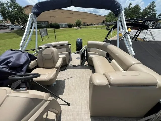 Slide: The Image of 2023 Starcraft LX18 R pontoon boat with beige seating and canopy, parked on grass. - 7