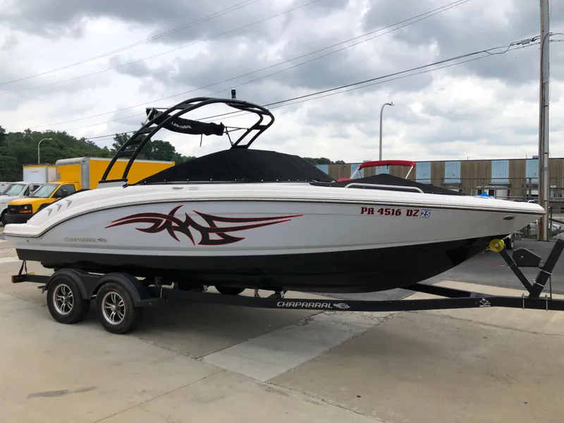 Slide: The Image of 2021 Chaparral 23 SSi boat on trailer, white with red graphics, parked outdoors. - 0