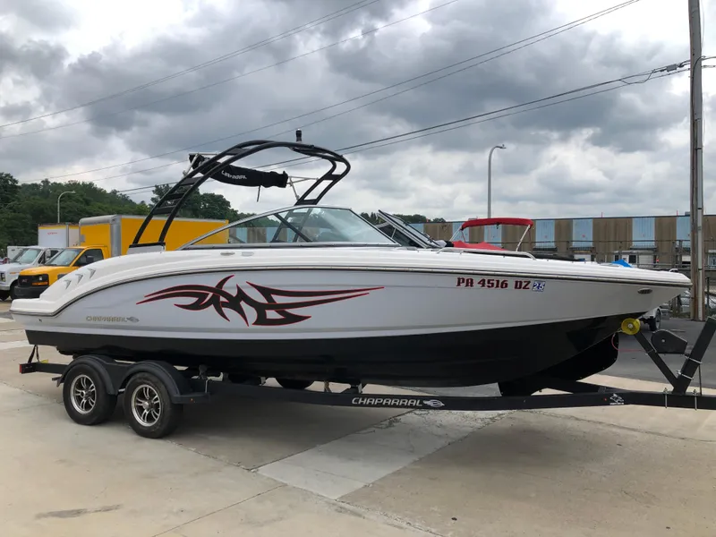 Slide: The Image of 2021 Chaparral 23 SSi boat on trailer, white with red graphics, parked outdoors. - 3